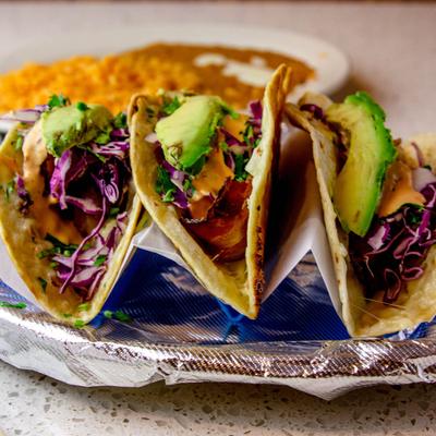 Tacos, with onions, cilantro, red cabbage, chipotle sauce, and avocado.