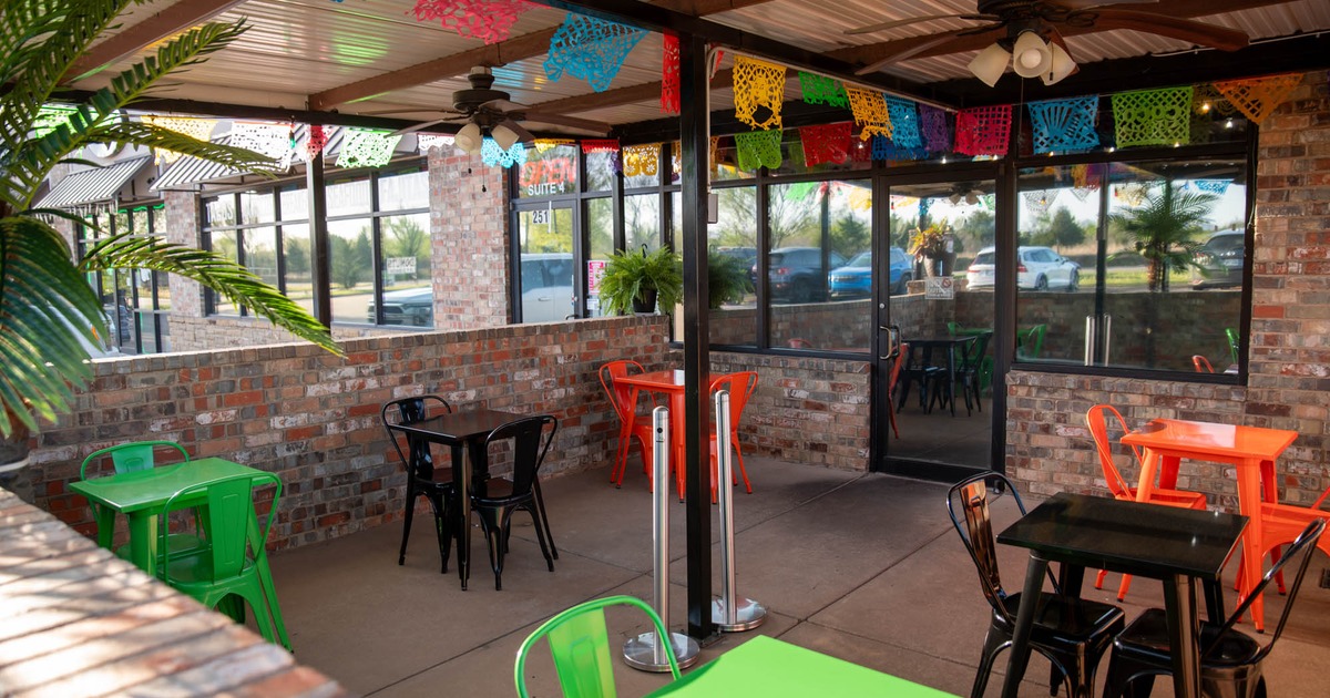 Exterior, patio, entrance, covered seating area, colorful tables for two people