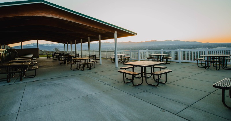 Outdoor dining area with several black metal picnic tables under a wooden roof