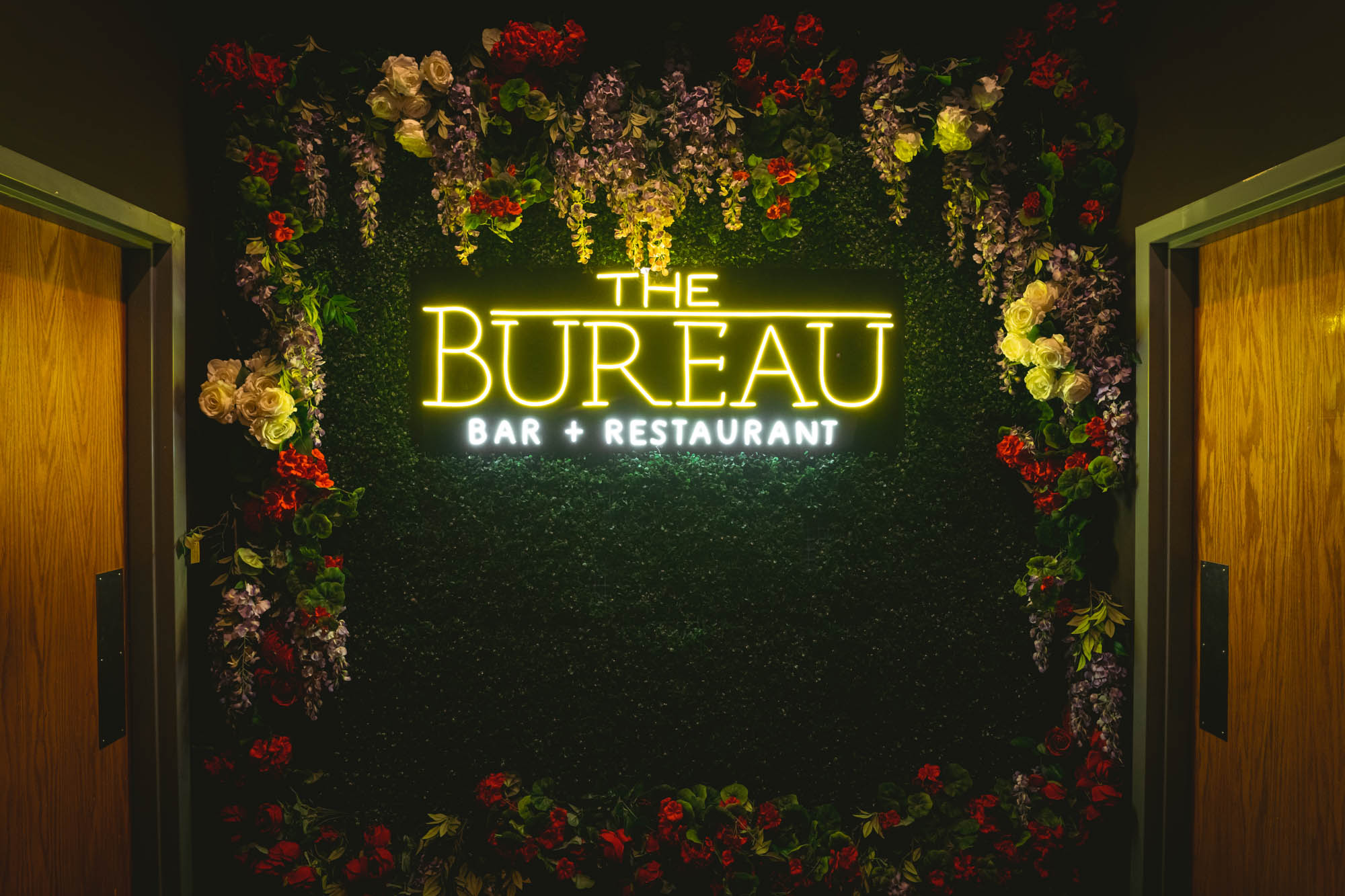 Interior, faux greenery and flower wall with the Bureau neon logo