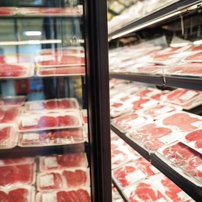 Commercial refrigerator case stocked with various cuts of fresh meat.