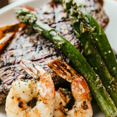 Grilled steak accompanied by grilled shrimp and asparagus, close-up.