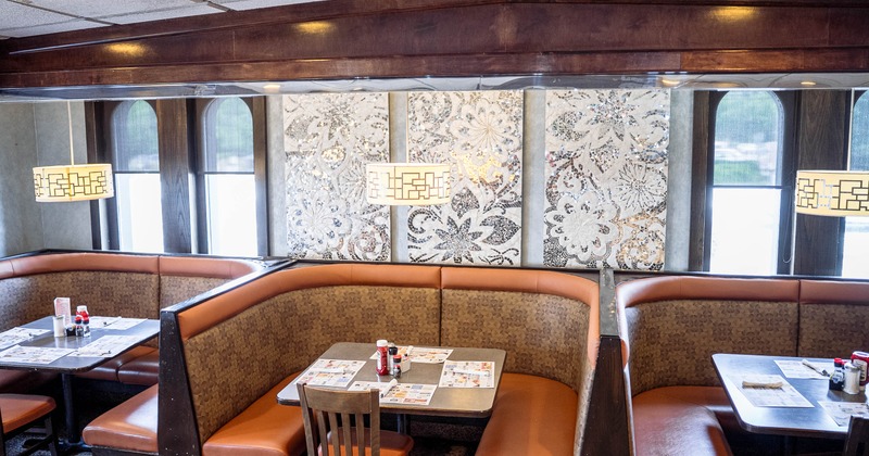 Cozy booth area - orange & brown seating, decorative floral wall panels & pendant lighting.
