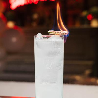 A cocktail with a flaming lime garnish.