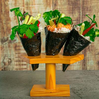 Three hand-rolled sushi rolls on a wooden stand.