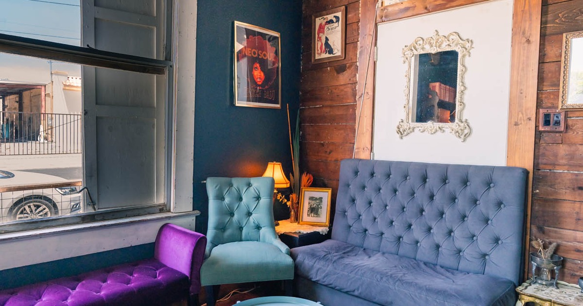 Lounge area with purple, teal, and gray upholstered furniture, coffee tables, and a patterned rug