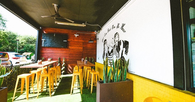 Covered patio with tables, yellow chairs, and a mural