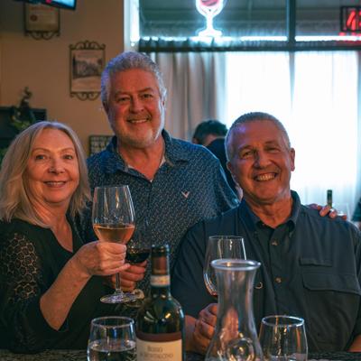 Three people raising wine glasses together.