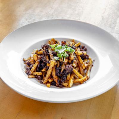 Bowl of fries with dark meat and chopped scallions.