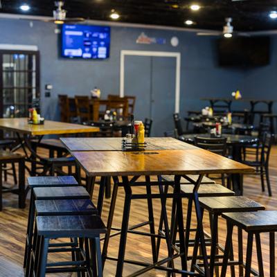 Interior with high top tables, stools and TV screen on the wall.