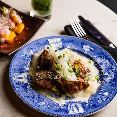 Masitas de Cerdo at Calle Dragones, served on a blue plate with yuca and mojo.