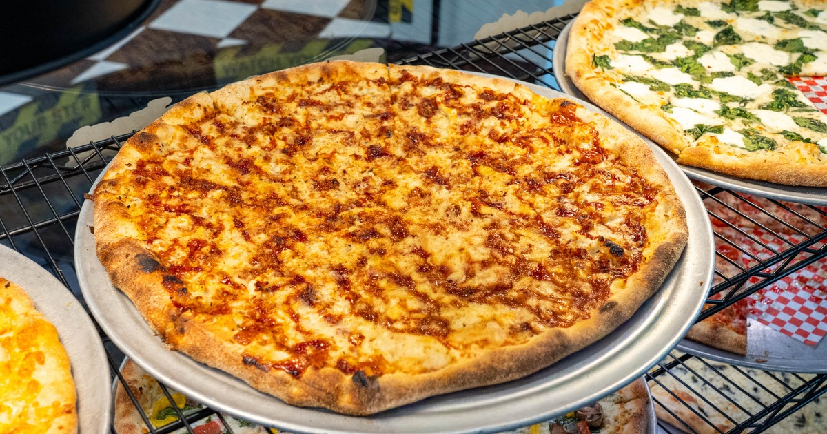 Golden thin-crust pizza topped with melted cheese and a red sauce drizzle