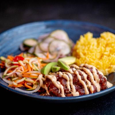 A colorful plate - drizzled meat, a salad with julienned vegetables, a mound of fluffy yellow rice.