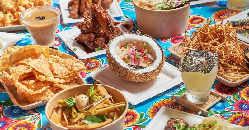 A vibrant spread of diverse Asian dishes and drinks on a colorful floral tablecloth