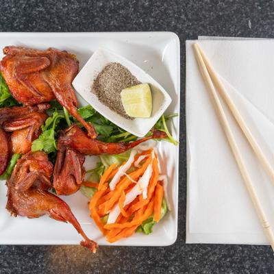 Vietnamese fried quail served with a side of salt, pepper and fresh garnsihes.