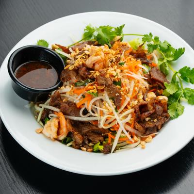 Green papaya salad with shrimp, pork, peanuts, and a side of sauce.