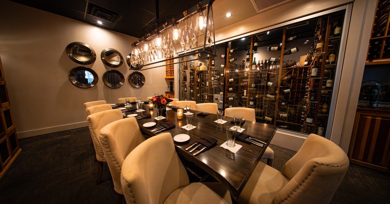 Modern, intimate and cozy wine room with a long wooden table set for twelve guests