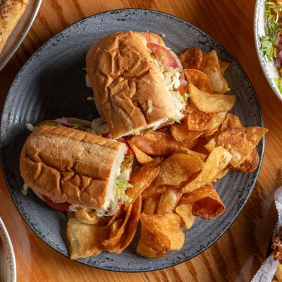 New York Italia sub sandwich served with potato chips, overhead view.