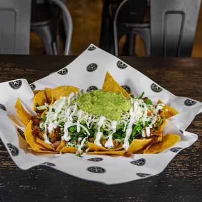 Chicken nachos, with beans, cheese, lettuce, avocado sauce, and sour cream.