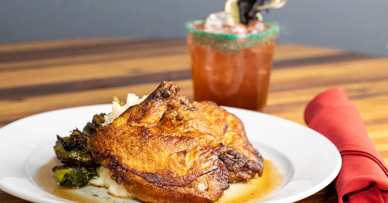Roasted half chicken on mashed potatoes with brussels sprouts and a cocktail drink