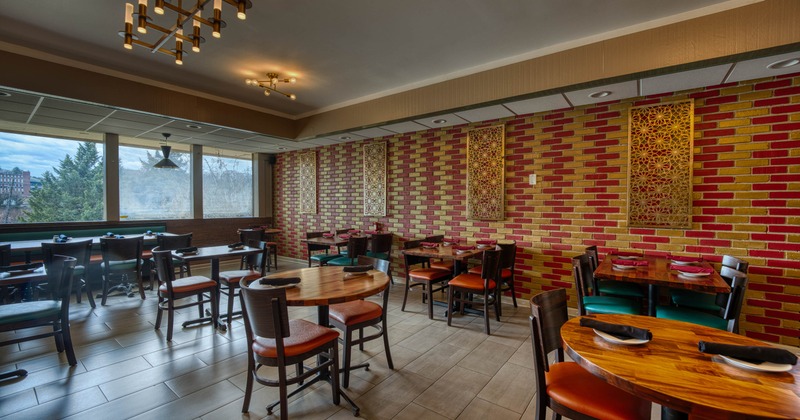 Interior with wooden tables and chairs, decorative brick wall, and large windows