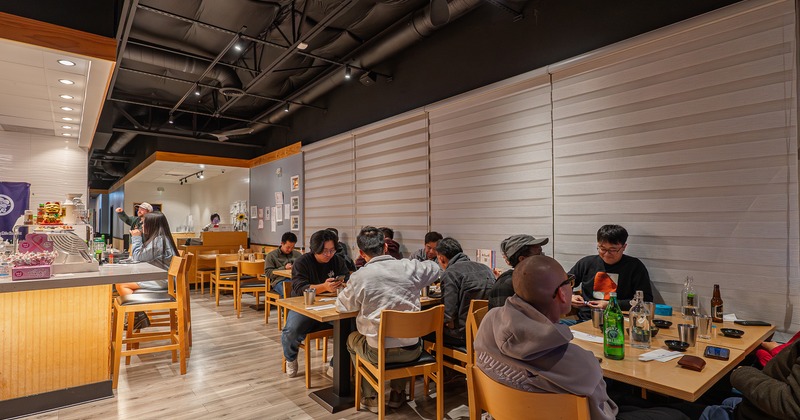 Modern and cozy sushi restaurant interior seating area with guests enjoying their food