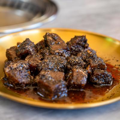 Seasoned and grilled beer chunks served on a gold-toned or brass plate.