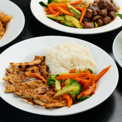 Grilled chicken strips served with rice and colorful vegetables.