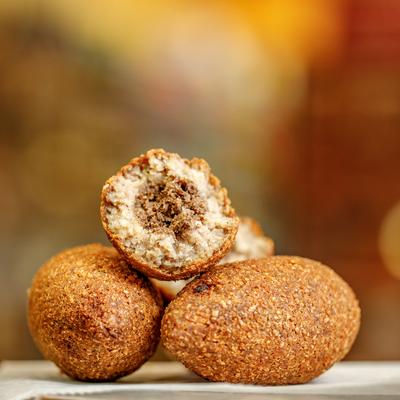 Three kibbeh balls, one cut in half, showing the meat filling.