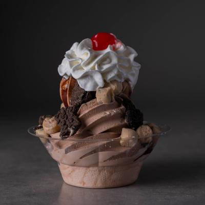 A layered chocolate sundae topped with whipped cream, a red cherry, cookies.