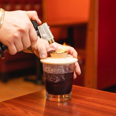 Cocktail being smoked with torch and smoking tip.