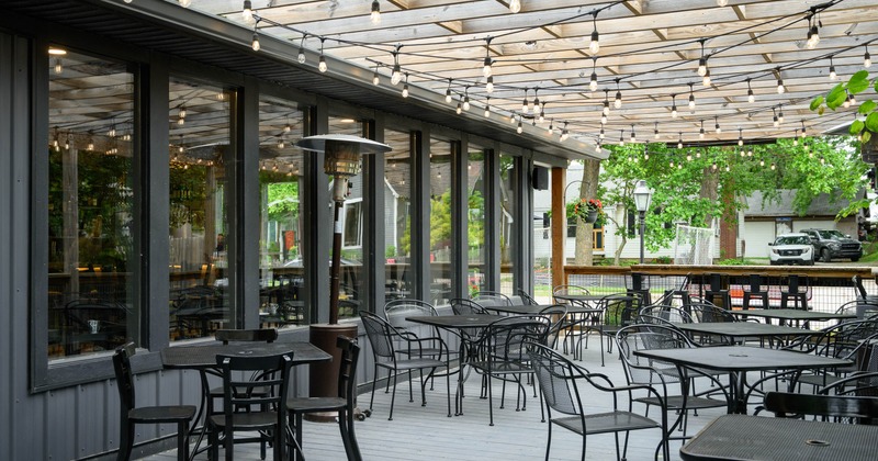 Covered outdoor dining area with tables, chairs, and string lights
