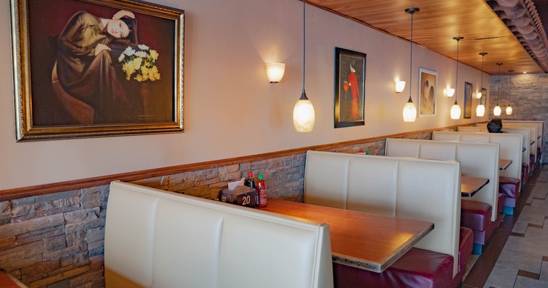 Interior of a restaurant with booths, framed artwork on the wall, and pendant lighting