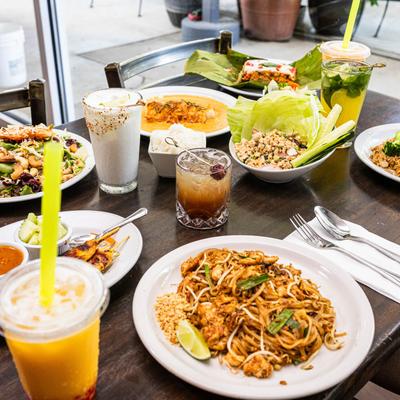 Thai dishes and drinks arranged on a wooden table.