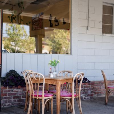 Outdoor seating with a table, chairs, and flowers and condiments on the table.