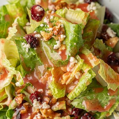 Romaine salad with cranberries, walnuts, feta cheese, and vinaigrette dressing.