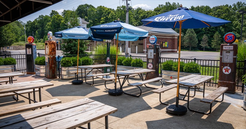 Outdoor seating area with wooden picnic tables and large umbrellas