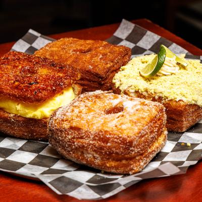 Four distinct croissant donuts served on a checkered paper.