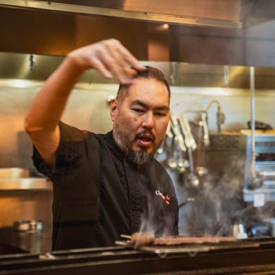Chef working over the grill with meat.