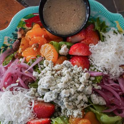 A salad with strawberries, tangerines, gorgonzola, pickled onions, and almonds.
