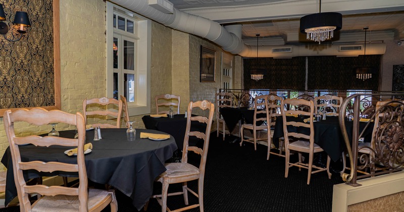Elegant restaurant interior with wooden chairs, black tablecloths, ornate wallpaper