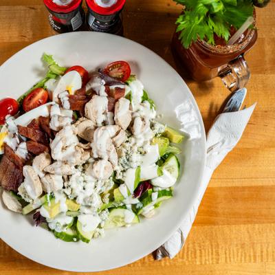 Large salad with chicken and creamy dressing, accompanied with a Bloody Mary.