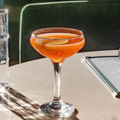 Naked and Famous cocktail in a coupe, gaarnished with a orange wheel.