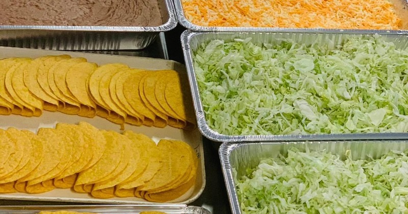 Buffet-style taco bar setup with taco shells and toppings