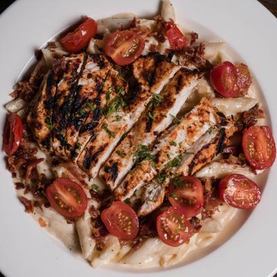 Blackened Chicken Bacon Alfredo garnished with cherry tomatoes.