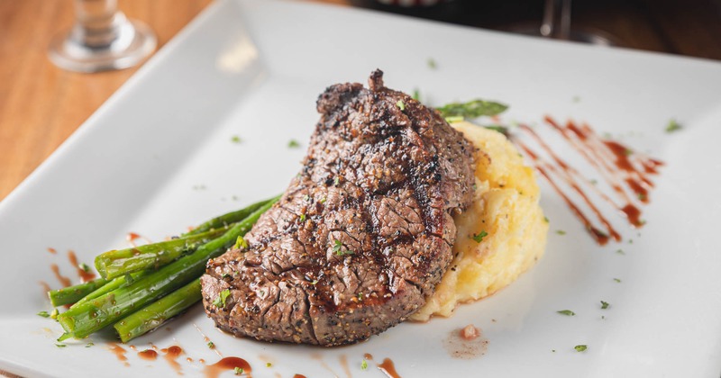Grilled steak with herbs on mashed potatoes, accompanied by asparagus