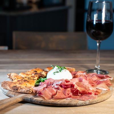 Prosciutto with flatbread and cheese, with a glass of wine on the side
