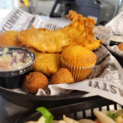 Fried fish with hush puppies, cornbread, and coleslaw on the side.