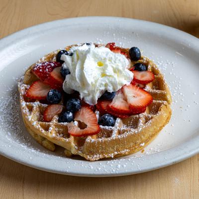 Waffle topped with berries, whipped cream and powdered sugar.