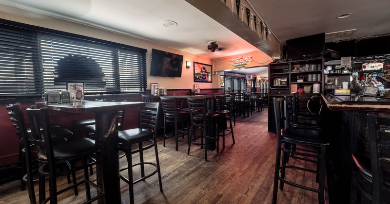 Interior, high seating area, bar stools, bar on the right, large TV on the wall